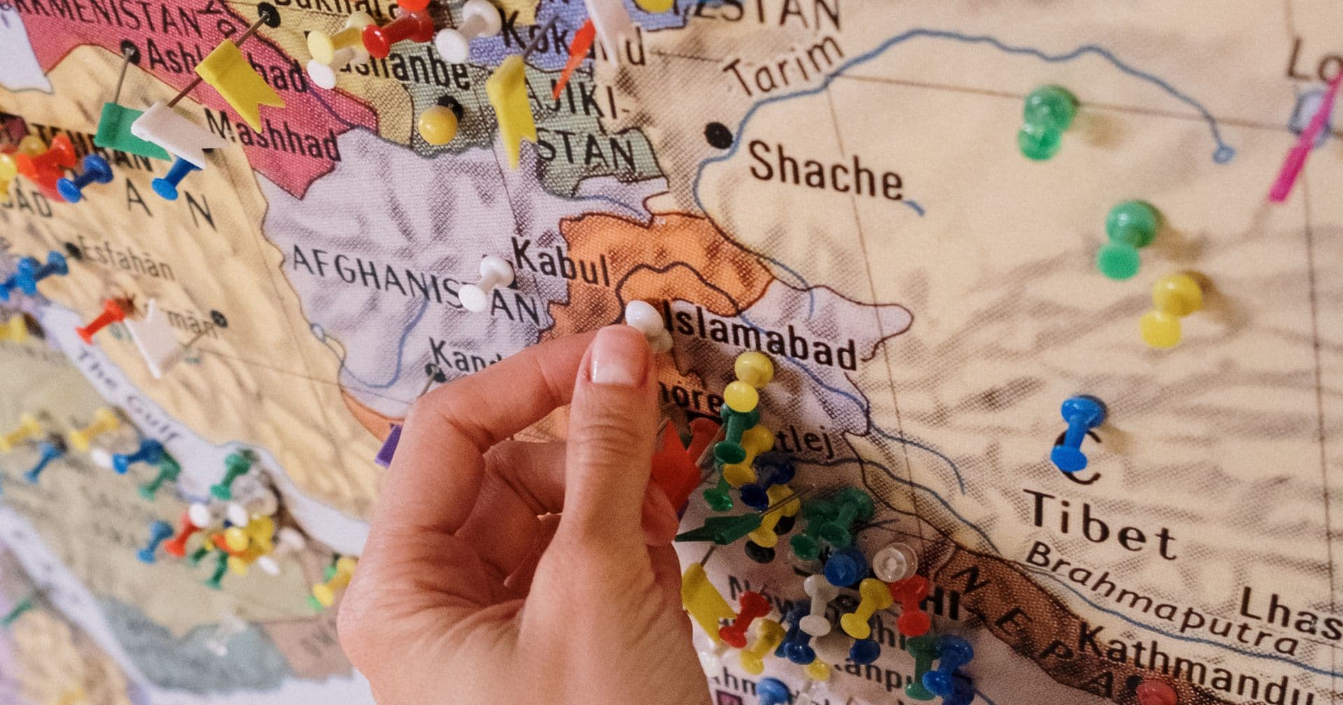 A hand placing location pins on a map — like local SEO putting a business on the map for nearby customers