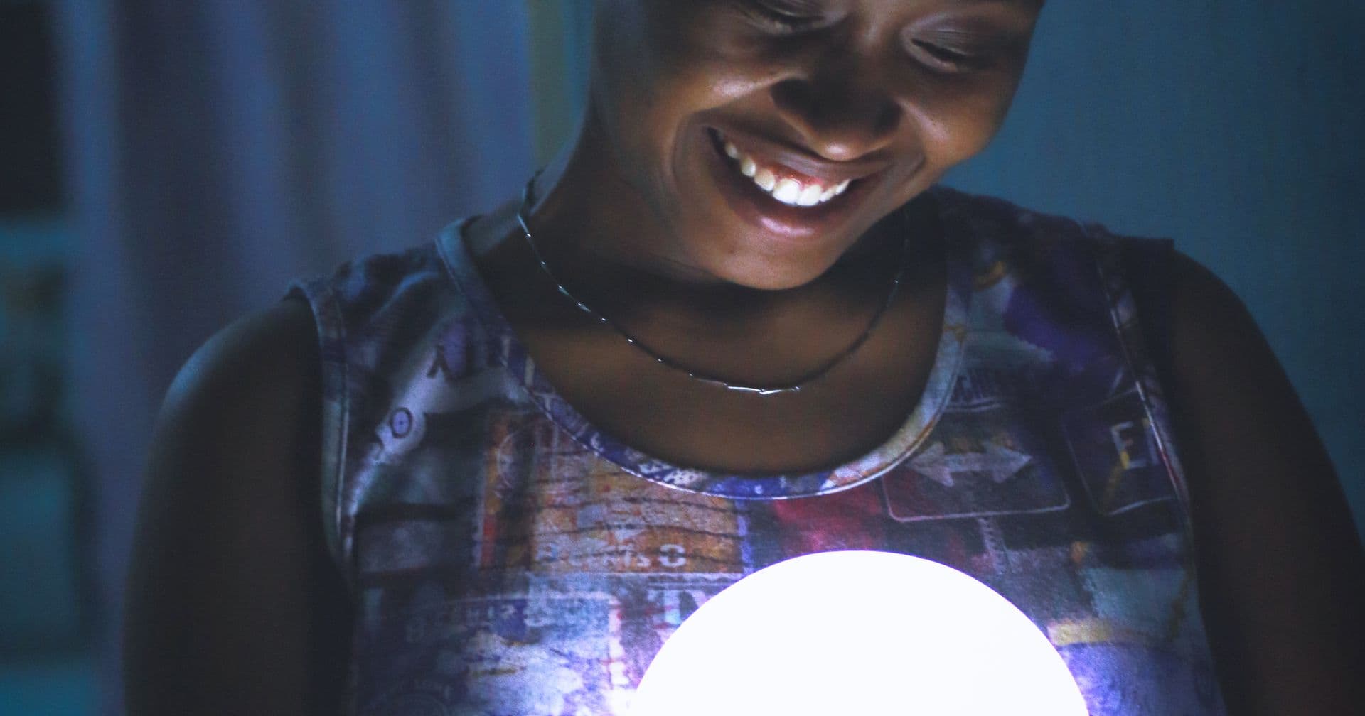 A person smiling warmly at a glowing orb of light, representing a friendly, approachable AI assistant